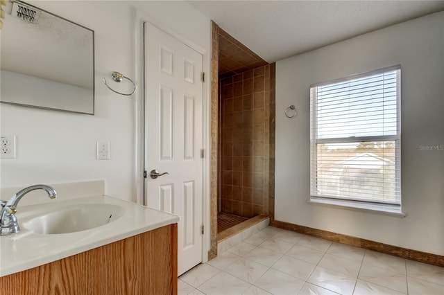 bathroom featuring tile patterned flooring, vanity, and tiled shower