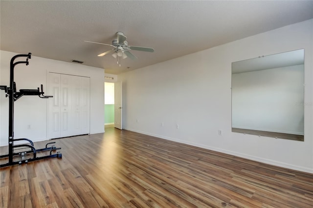 exercise area featuring ceiling fan, wood-type flooring, and a textured ceiling