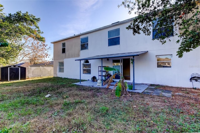 back of property with a lawn, a patio, and a storage unit