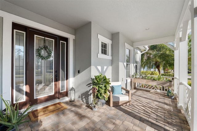 entrance to property featuring covered porch and stucco siding