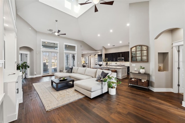 living room with ceiling fan, dark hardwood / wood-style floors, and high vaulted ceiling