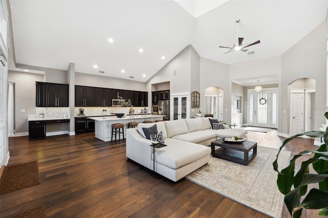 living room with dark hardwood / wood-style flooring, sink, high vaulted ceiling, and ceiling fan