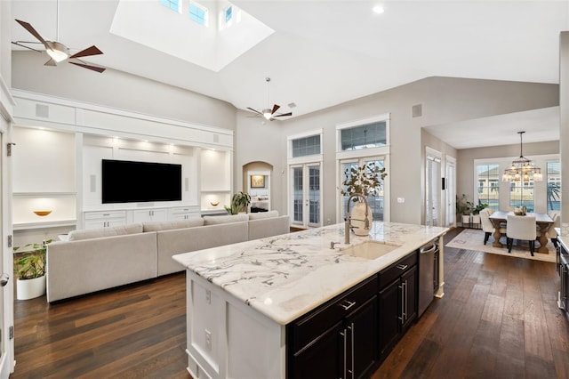 kitchen with pendant lighting, ceiling fan with notable chandelier, dishwasher, sink, and a center island with sink