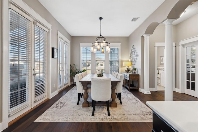 dining space with french doors, dark hardwood / wood-style floors, a chandelier, and ornate columns