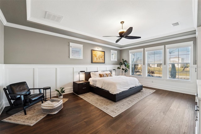 bedroom with dark wood-type flooring, ceiling fan, a tray ceiling, and crown molding