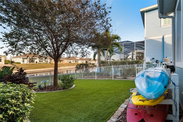 view of yard featuring a lanai, fence, a water view, and a residential view