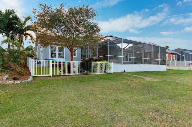 rear view of property featuring a lanai, a yard, and fence