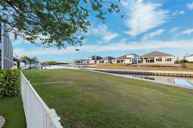 view of yard featuring fence, a water view, and a residential view