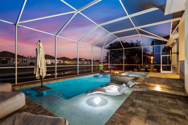 pool at dusk featuring an in ground hot tub, a lanai, and a patio area