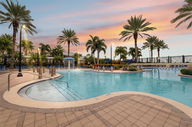 pool at dusk featuring a patio and pool water feature