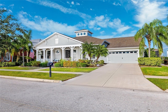 view of front of house with an attached garage, a front yard, covered porch, and driveway