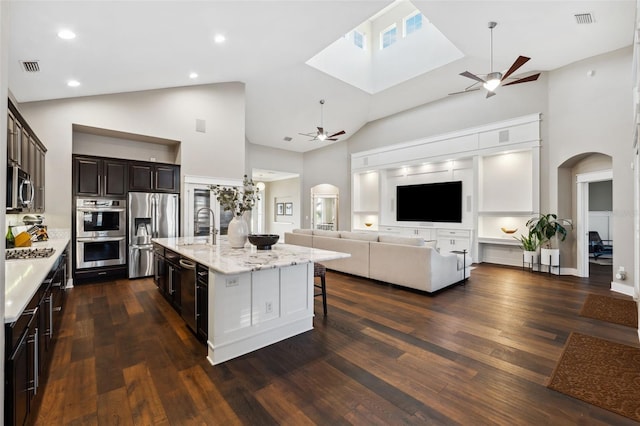 kitchen featuring visible vents, open floor plan, stainless steel appliances, arched walkways, and ceiling fan