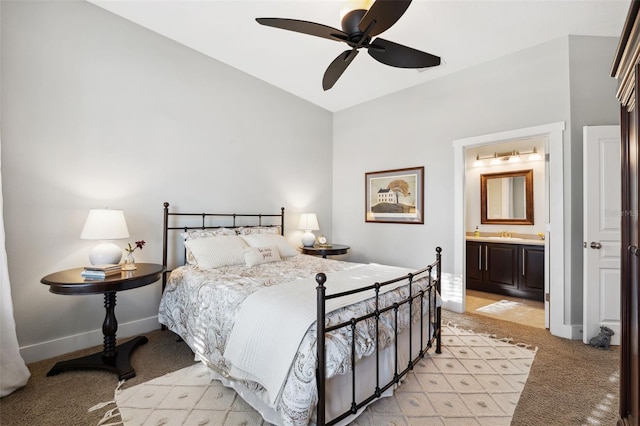 bedroom with ceiling fan, ensuite bath, baseboards, and light carpet