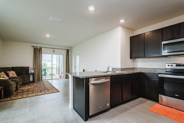 kitchen featuring stone countertops, sink, light tile patterned floors, kitchen peninsula, and stainless steel appliances