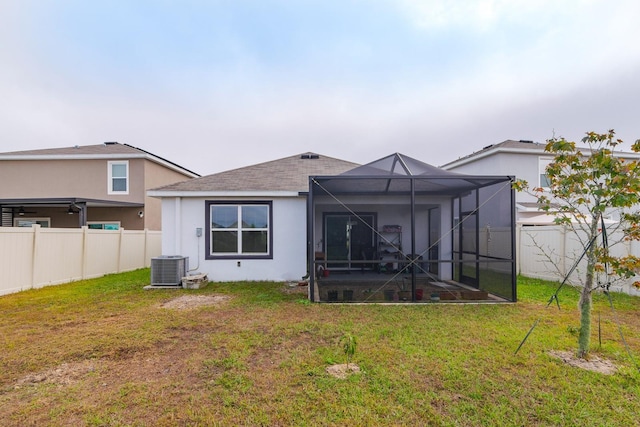 back of property featuring a lanai, a lawn, and central AC