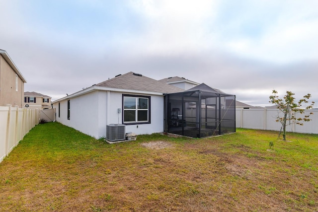 back of property with a yard, a lanai, and central AC unit