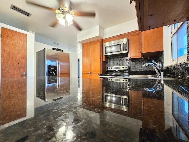 kitchen featuring ceiling fan, sink, dark stone countertops, decorative backsplash, and appliances with stainless steel finishes