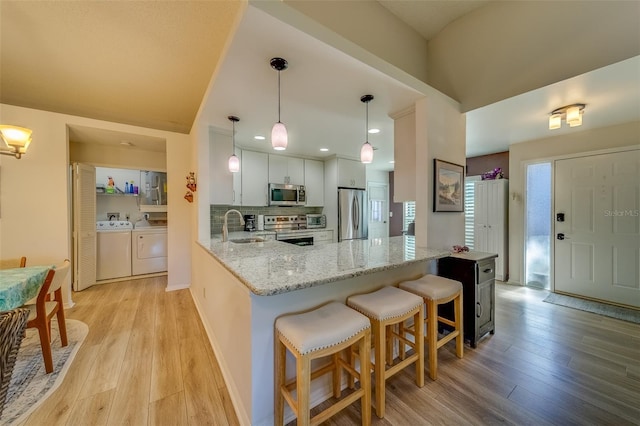 kitchen with pendant lighting, sink, a breakfast bar area, kitchen peninsula, and stainless steel appliances