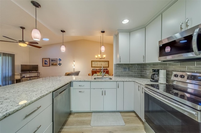 kitchen with appliances with stainless steel finishes, backsplash, vaulted ceiling, sink, and pendant lighting