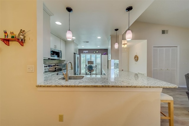 kitchen with stainless steel appliances, tasteful backsplash, kitchen peninsula, decorative light fixtures, and a kitchen bar