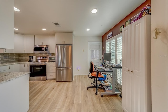 kitchen featuring backsplash, light stone counters, stainless steel appliances, light hardwood / wood-style flooring, and white cabinets