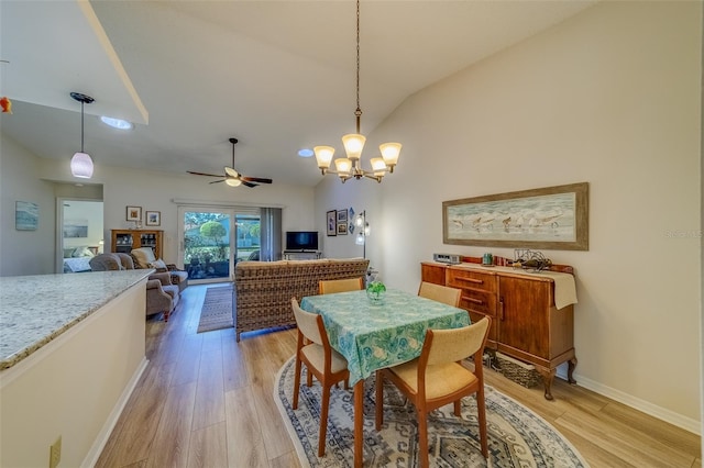 dining room with ceiling fan with notable chandelier, light hardwood / wood-style floors, and vaulted ceiling