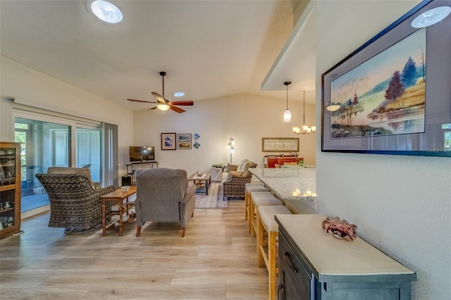 living room featuring ceiling fan with notable chandelier, light hardwood / wood-style floors, and vaulted ceiling