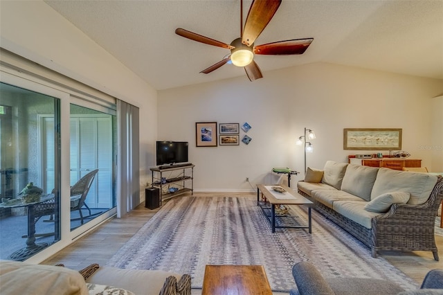 living room with ceiling fan, lofted ceiling, a textured ceiling, and light hardwood / wood-style flooring