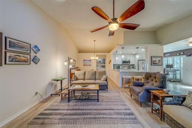 living room featuring ceiling fan with notable chandelier, light wood-type flooring, a textured ceiling, and high vaulted ceiling