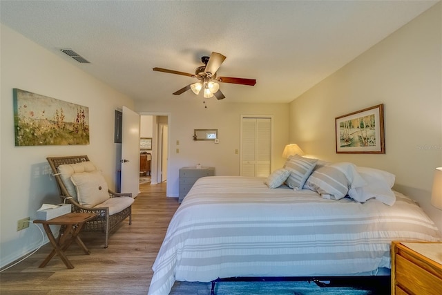 bedroom with hardwood / wood-style floors, a textured ceiling, a closet, and ceiling fan