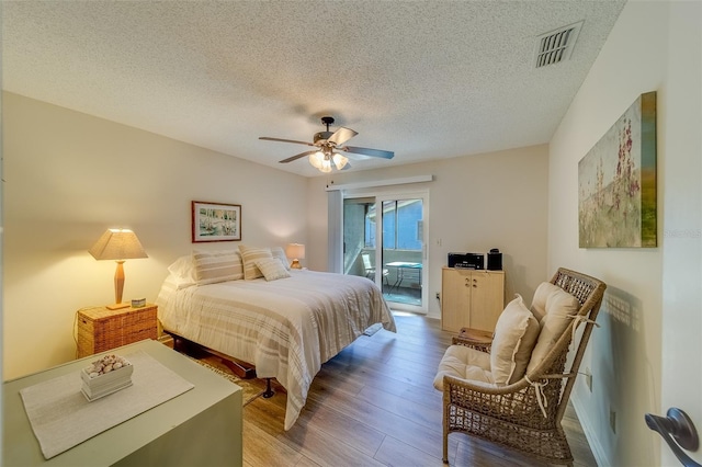 bedroom featuring hardwood / wood-style floors, ceiling fan, a textured ceiling, and access to outside