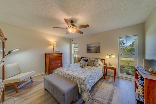 bedroom featuring ceiling fan, light wood-type flooring, and a textured ceiling