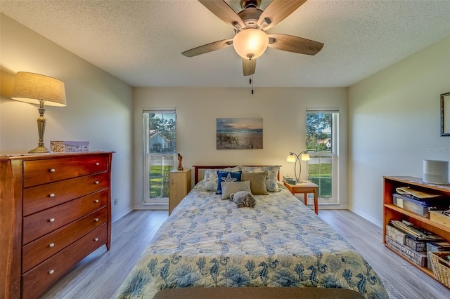 bedroom featuring ceiling fan, light hardwood / wood-style floors, and a textured ceiling