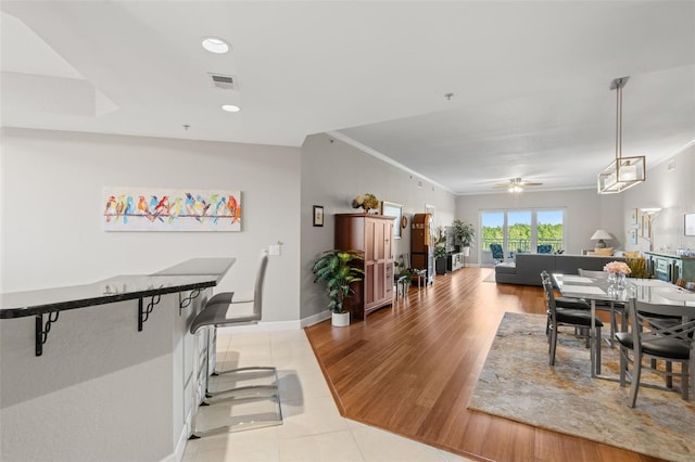 dining area with ceiling fan, crown molding, and light hardwood / wood-style flooring