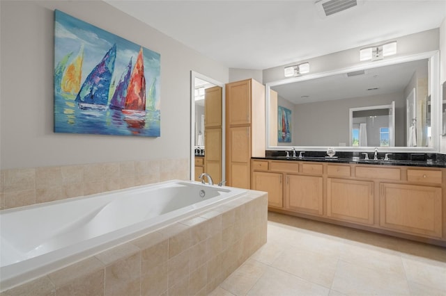 bathroom featuring tile patterned flooring, vanity, and a relaxing tiled tub