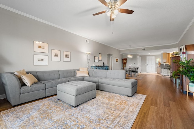 living room with light hardwood / wood-style flooring, ceiling fan, and crown molding