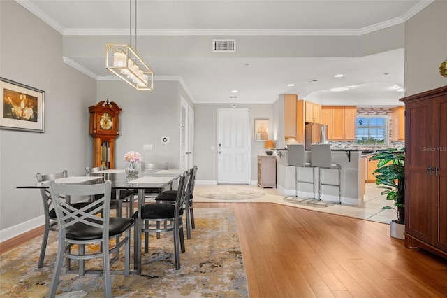 dining room featuring ornamental molding and light hardwood / wood-style flooring