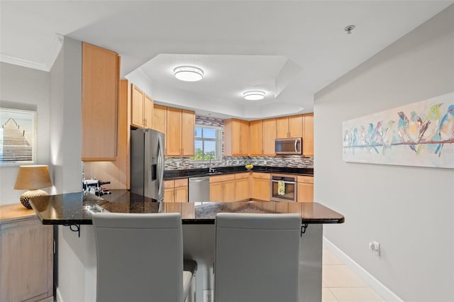 kitchen with backsplash, kitchen peninsula, a breakfast bar, light tile patterned floors, and appliances with stainless steel finishes