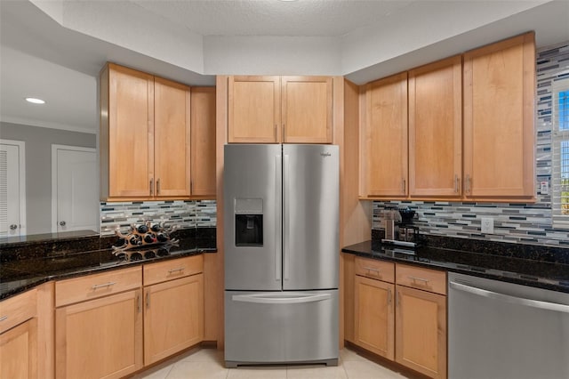 kitchen with appliances with stainless steel finishes, light brown cabinets, and dark stone counters