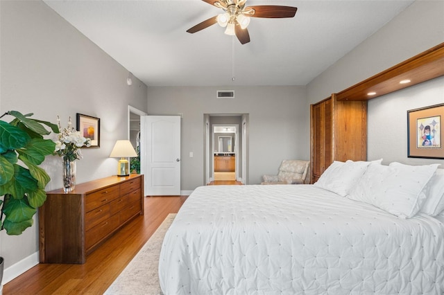 bedroom featuring light wood-type flooring, ensuite bath, and ceiling fan