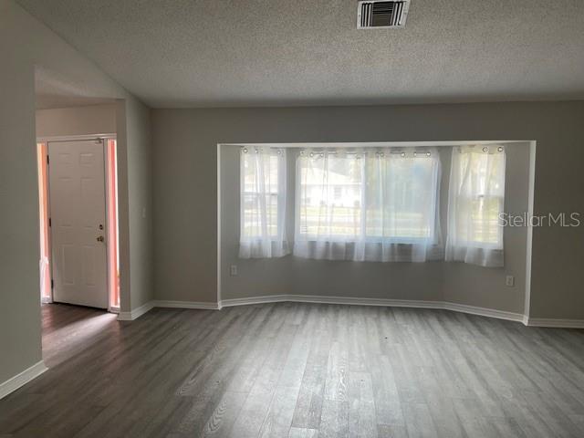 unfurnished room with hardwood / wood-style floors and a textured ceiling