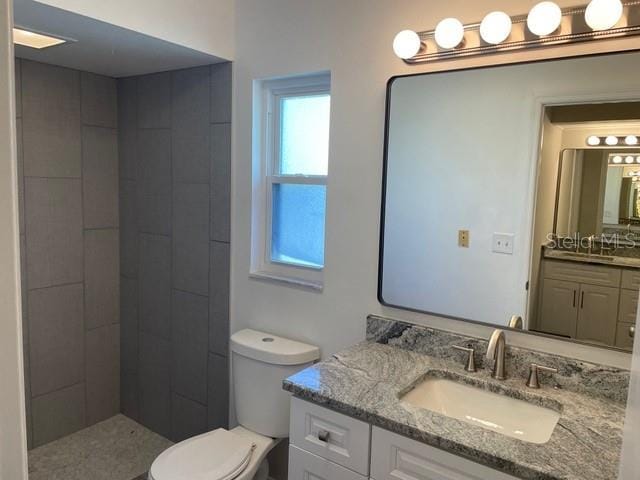 bathroom featuring vanity, toilet, and tiled shower