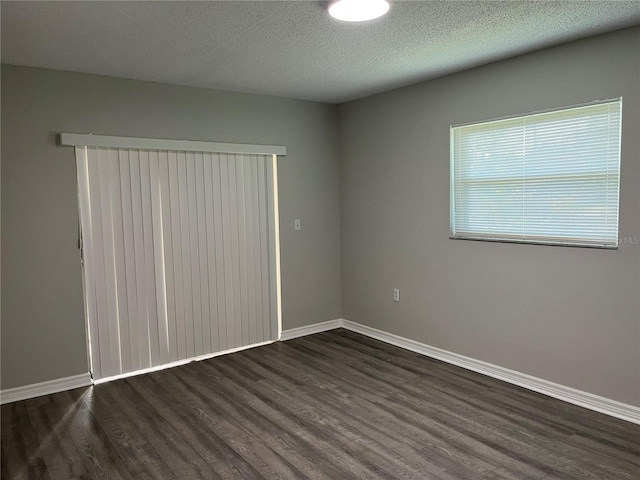 spare room featuring dark hardwood / wood-style flooring and a textured ceiling