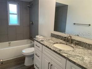 full bathroom featuring vanity, tiled shower / bath combo, hardwood / wood-style flooring, and toilet