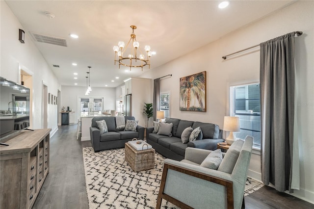 living room featuring french doors, dark wood-type flooring, and a notable chandelier