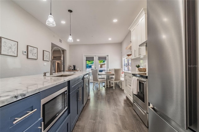 kitchen with sink, white cabinets, hanging light fixtures, and appliances with stainless steel finishes