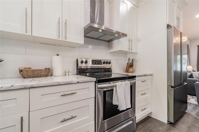 kitchen featuring wall chimney range hood, dark hardwood / wood-style floors, appliances with stainless steel finishes, tasteful backsplash, and white cabinetry