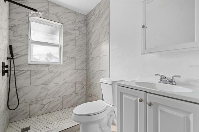 bathroom featuring a tile shower, toilet, and vanity