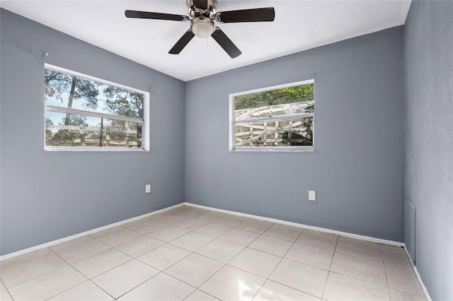 tiled spare room with ceiling fan and a wealth of natural light