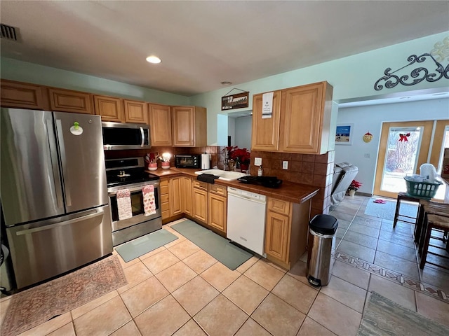 kitchen with decorative backsplash, sink, stainless steel appliances, tile counters, and light tile patterned floors